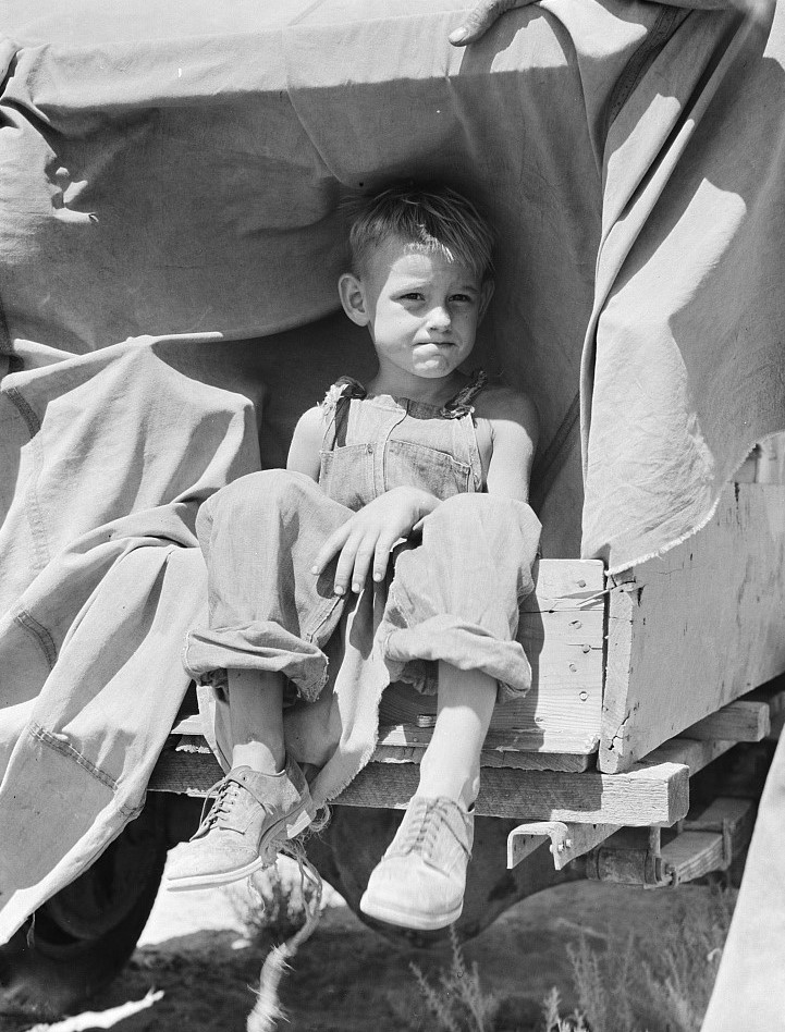 Photograph of a boy sitting in the back of a wagon
