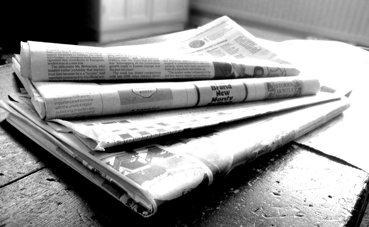 This is a black and white photo of a stack of newspapers