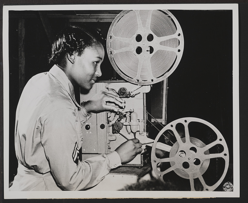 a black woman works and old school movie projector