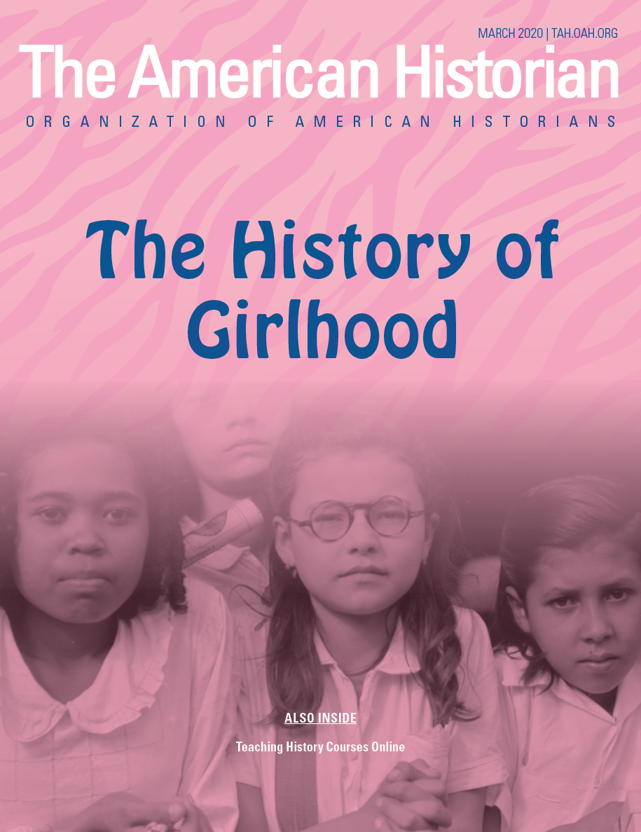The magazine's cover is pink zebra striped with blue writing for the title 'The History of Girlhood'. The image is 'black and white' of a group of young girls.