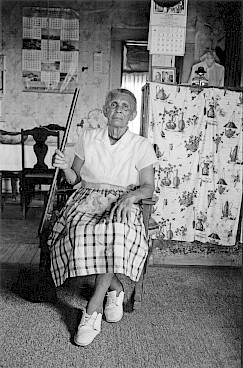 A woman is seated in her chair in her home in Alabama holding a shotgun