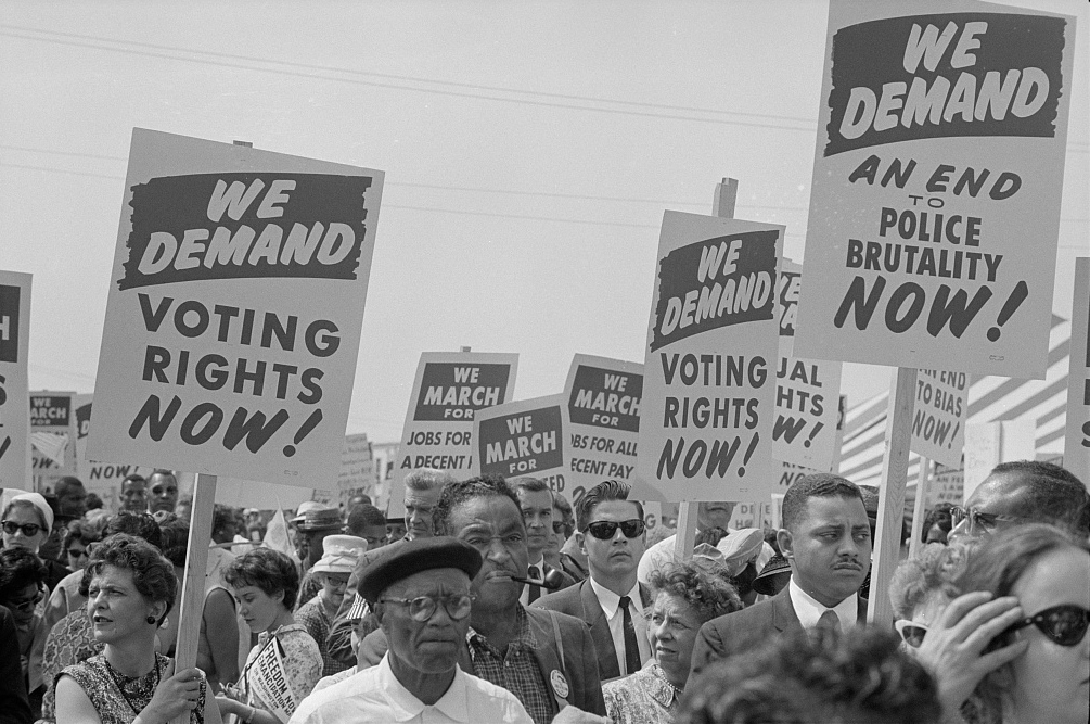 Multiple adults in a march carrying signs that read: 