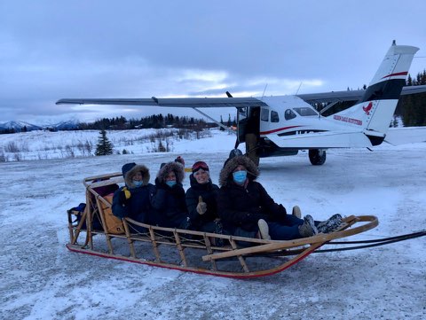 A group of healthcare workers are on a sled in Alaska, ready to deliver COVID-19 vaccines.